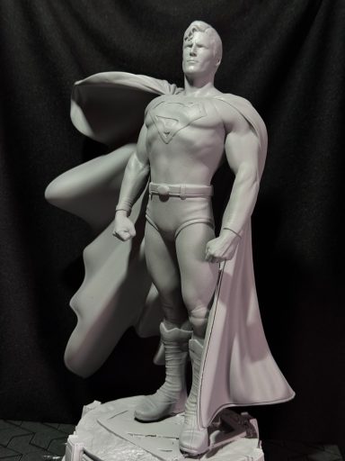 Estatua de un superhéroe musculoso con capa, de pie y en pose heroica.