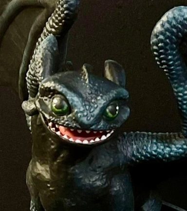 Dragón negro con alas, ojos verdes y una expresión feroz.