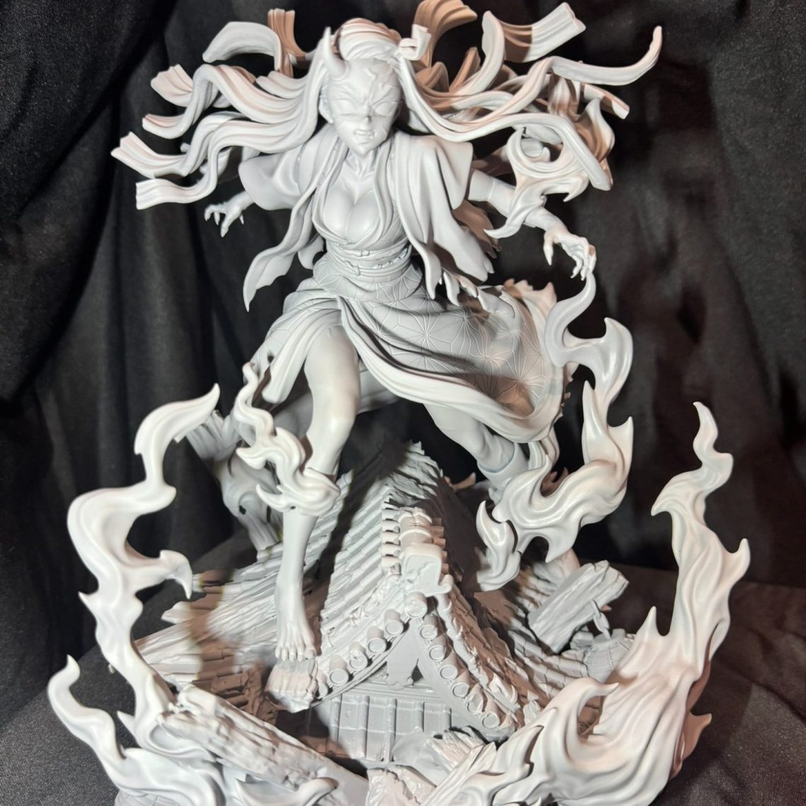 Escultura de una figura dinámica con cabello largo y llamas alrededor.