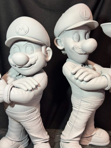Estatuas de Mario y Luigi en arcilla, con brazos cruzados y sonrisas.