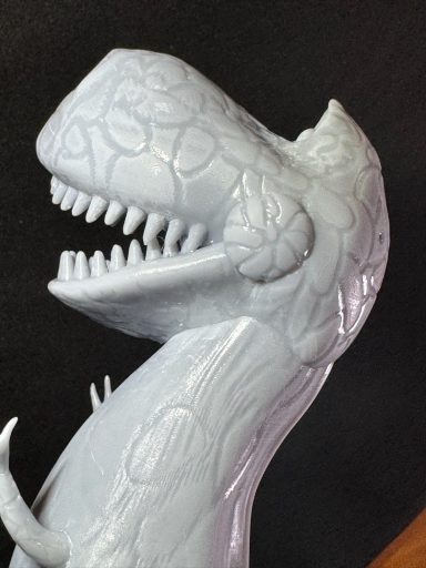 Escultura de dinosaurio T-Rex en color blanco mate con detalles en relieve.