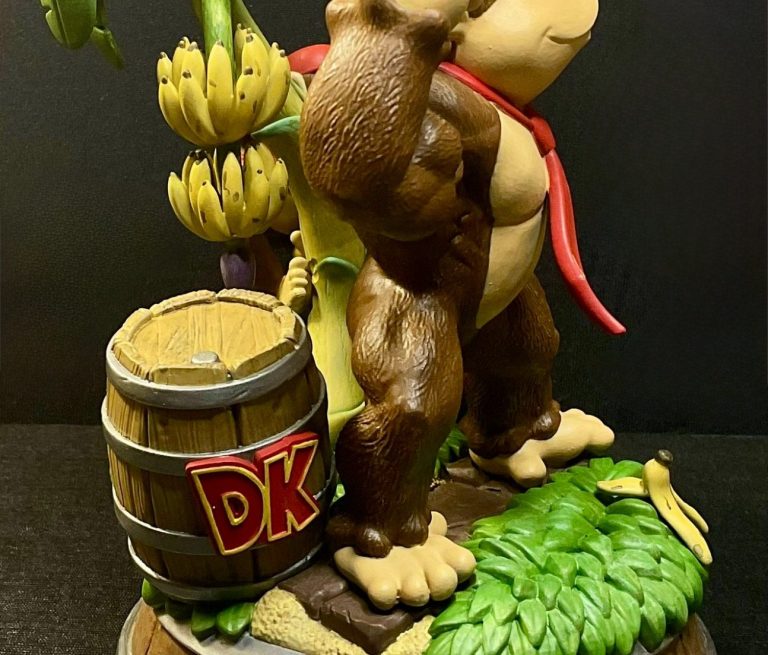 Figura de Donkey Kong sujetando un plátano, con un barril a su lado.