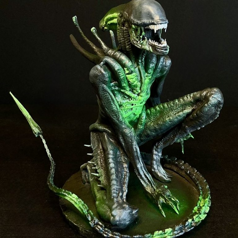 Escultura de un alienígena, con detalles en verde y una pose amenazante.