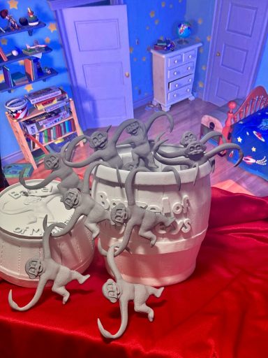 Esculturas de monos en una mesa roja, con un fondo de habitación infantil.